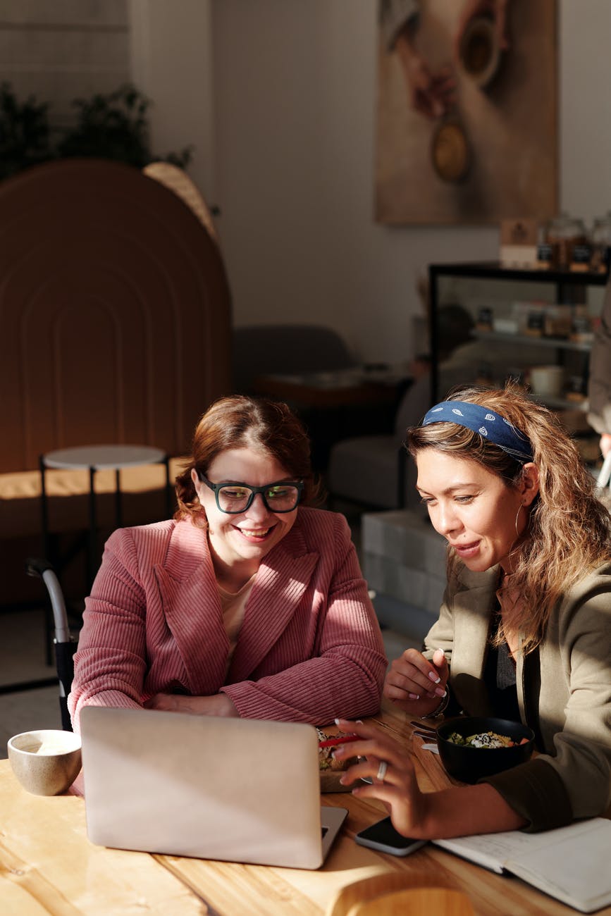 woman in pink blazer sitting beside woman in brown blazer